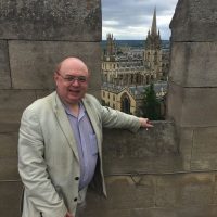 A picture of the author of the blog and book, David Bradbury. David is leaning on a wall overlooking a pretty cityscape