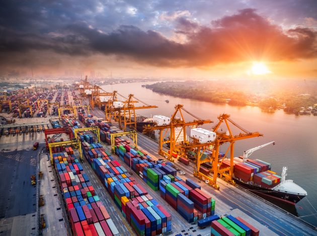 Image of cranes and shipping containers at a port, indicating trade