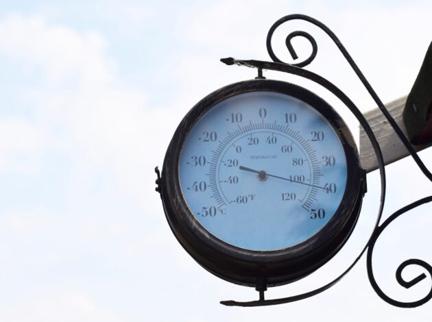 An old fashioned clock face style thermometer on a building in the South of the UK in 2022 showing 40 degrees Celsius as Britain experiences unprecedented record temperatures