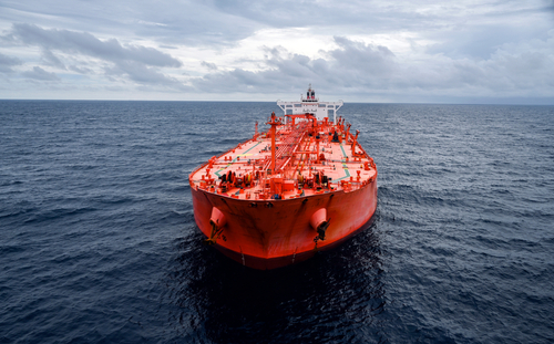 Image of a large red tanker sailing across a dark ocean